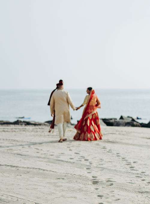 hindu-wedding-couple-walks-along-ocean-shore hindu-wedding-couple-walks-along-ocean-shore